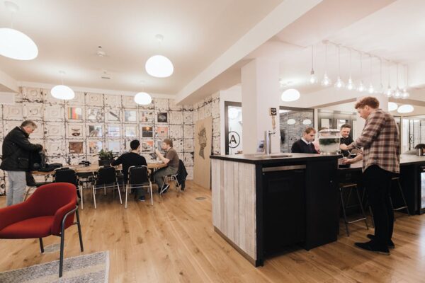 A modern, communal workspace in Sheraton Street, London, with people working and interacting.