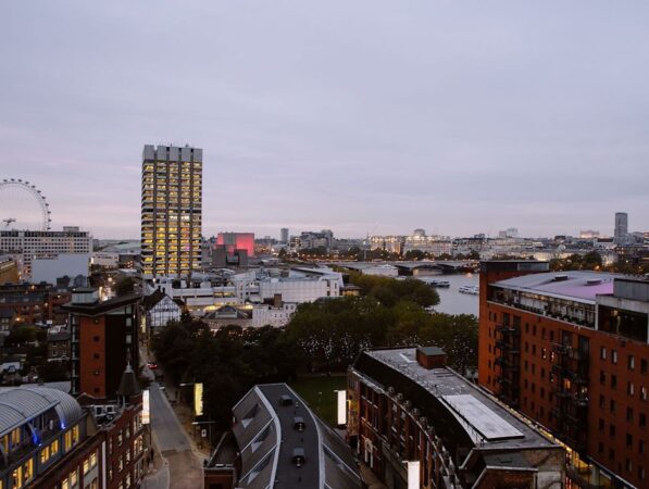 Aerial view of central London featuring the River Thames, the London Eye, and city buildings at dusk.