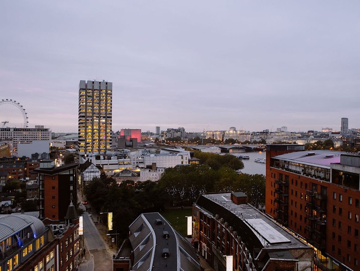 Aerial view of central London featuring the River Thames, the London Eye, and city buildings at dusk.