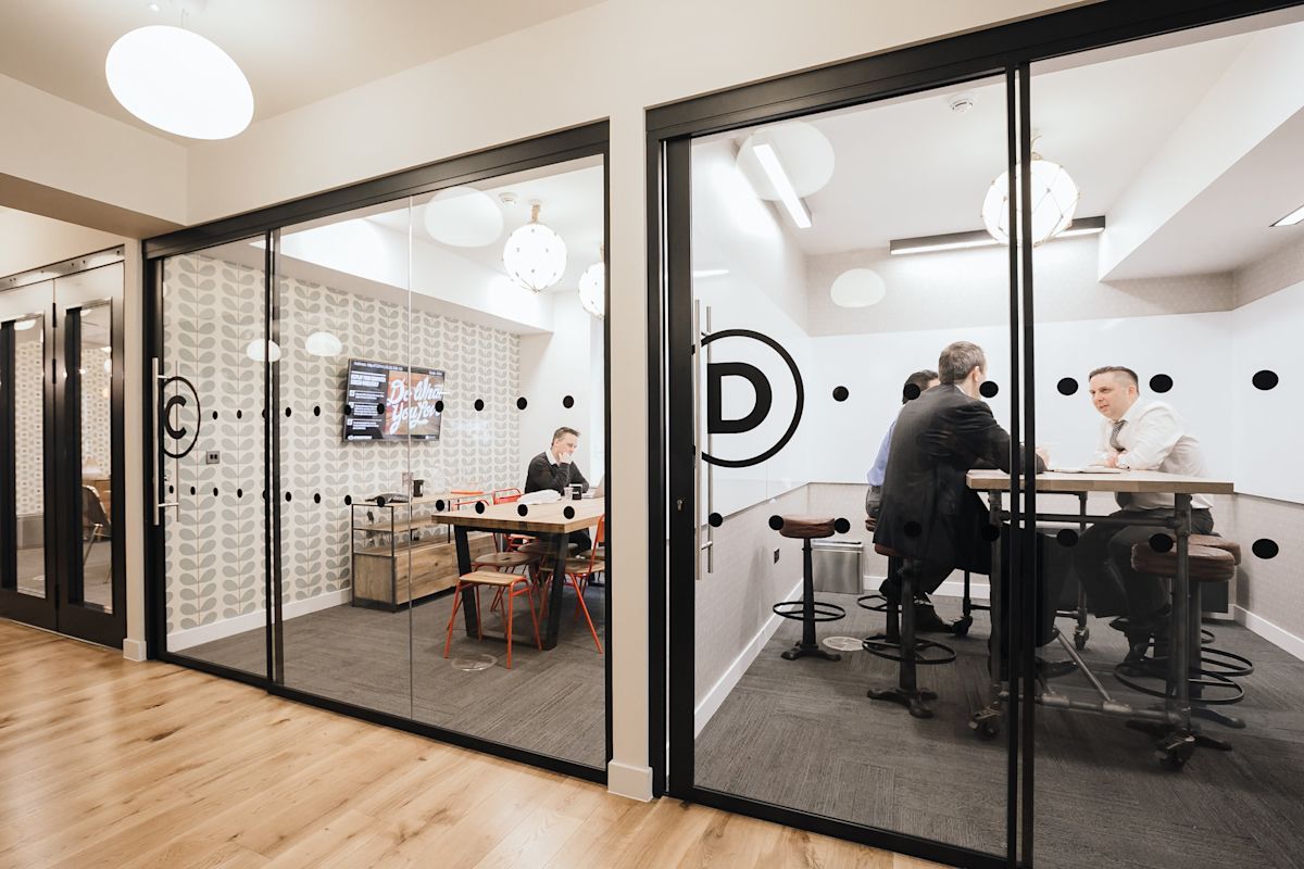 People having a meeting in a modern glass-walled office space.