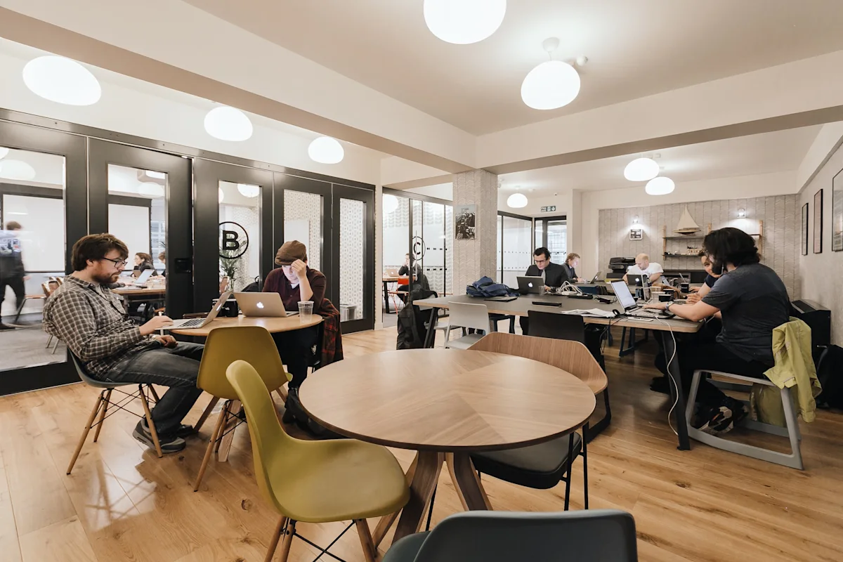 People working on laptops in a modern co-working space on Sheraton Street in London.