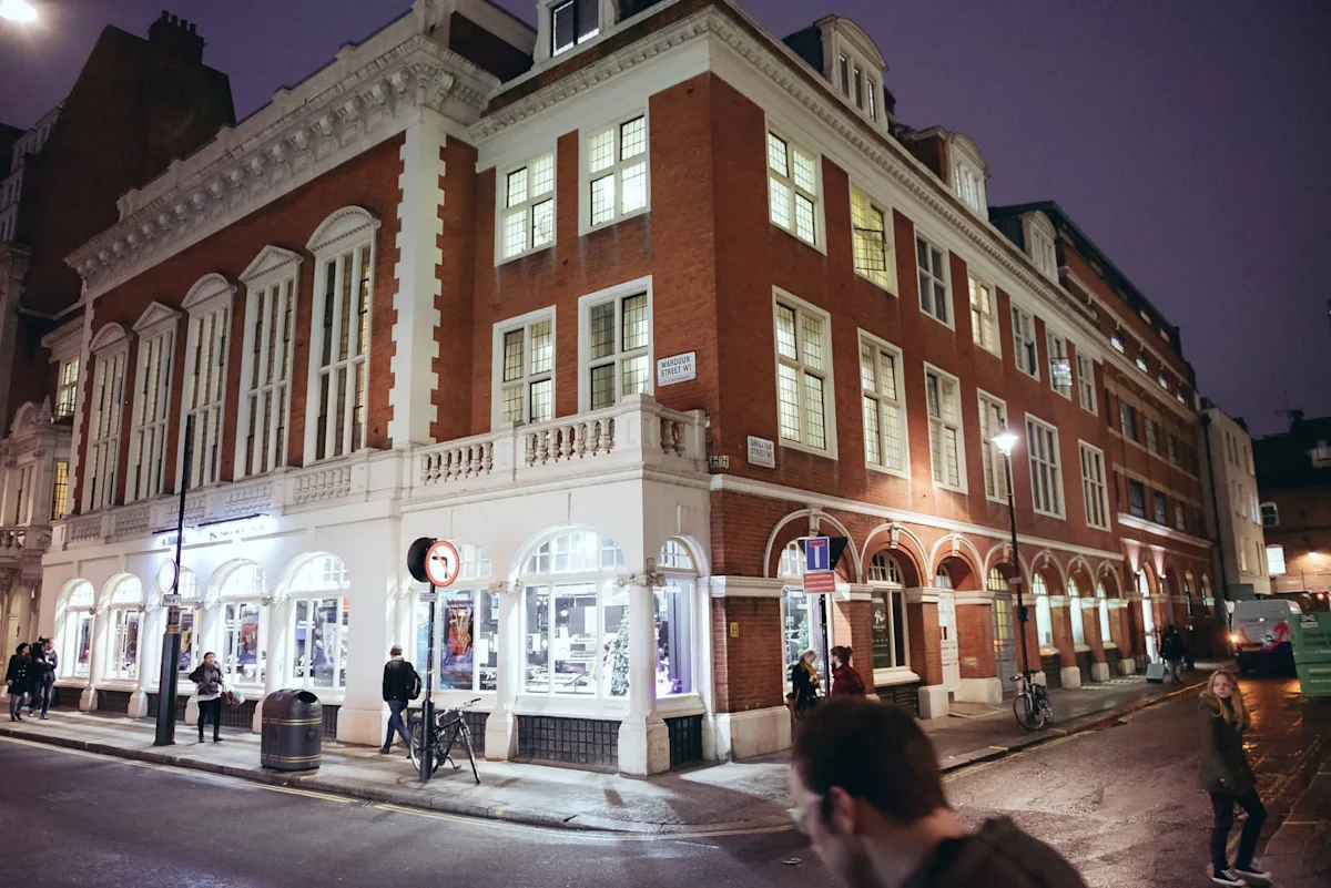 A nighttime street view of a historic brick building on Sheraton Street in London.