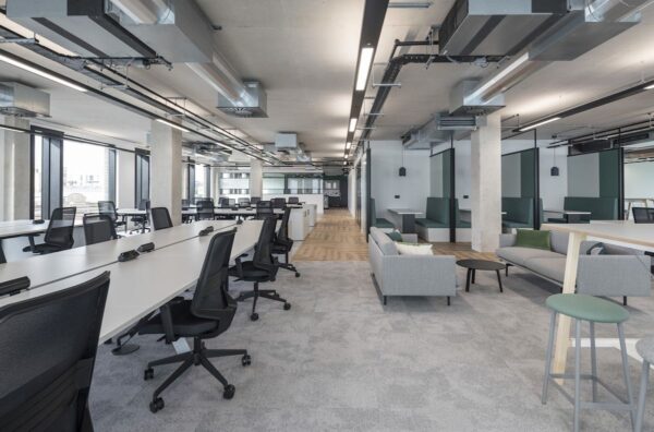 Modern open-plan office space with desks, chairs, and lounge area.