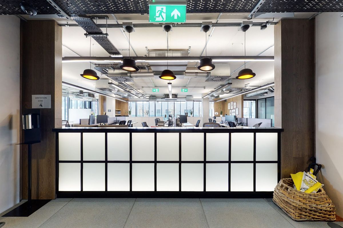 A modern office reception area with a backlit counter in Shoreditch High Street, London.