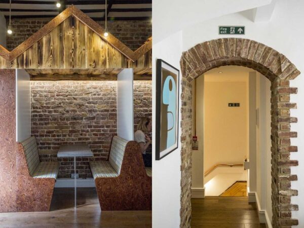 Cozy dining booth with wooden accents next to a brick archway leading to a corridor with a fire exit sign.