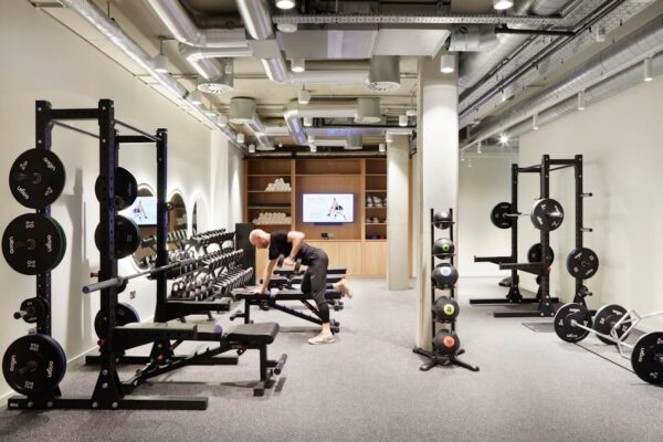 A modern gym on Shoreditch High Street with a person exercising with dumbbells.