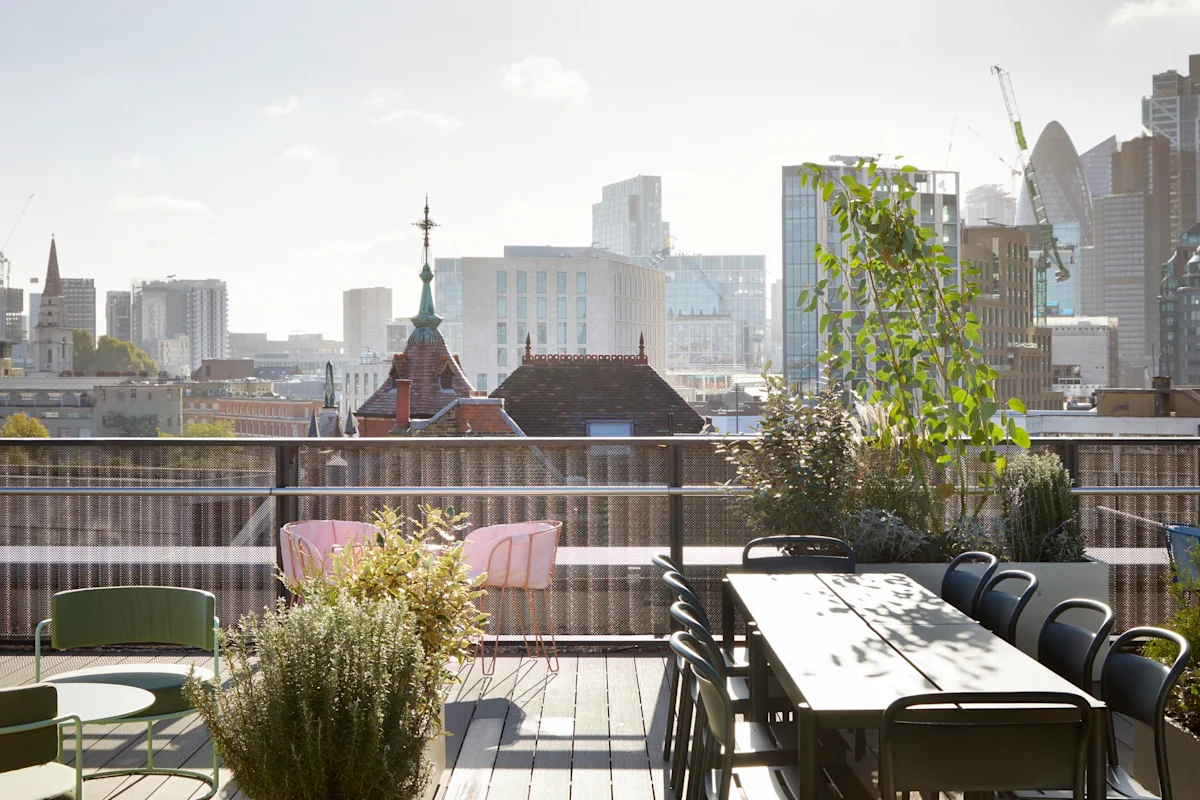 Rooftop terrace with plants and seating overlooking the skyline of Shoreditch High Street, London.