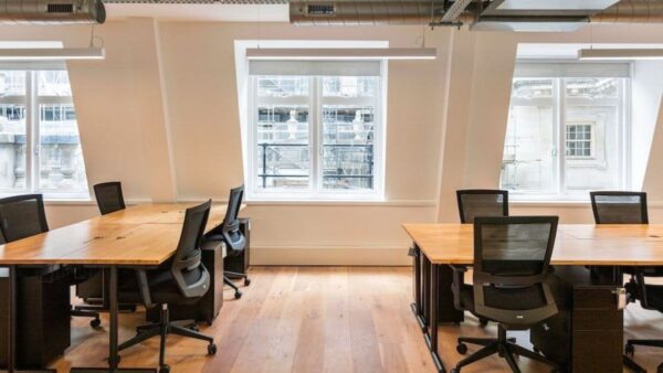 Modern office space with wooden desks and black chairs, located at St Helens Place 17, London.
