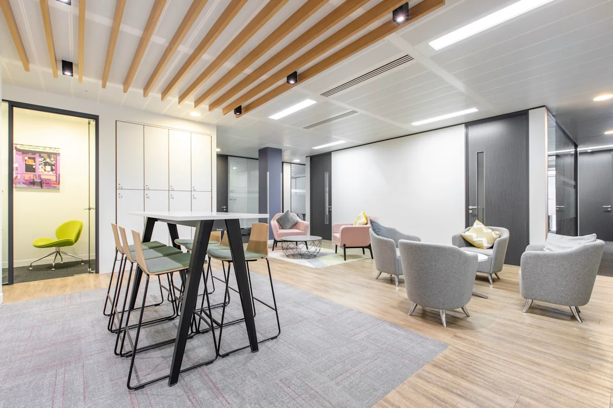 Modern office lounge area with stylish furniture and a high table at St Mary Axe 63, London.