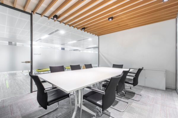 A modern conference room with a long white table and black chairs.