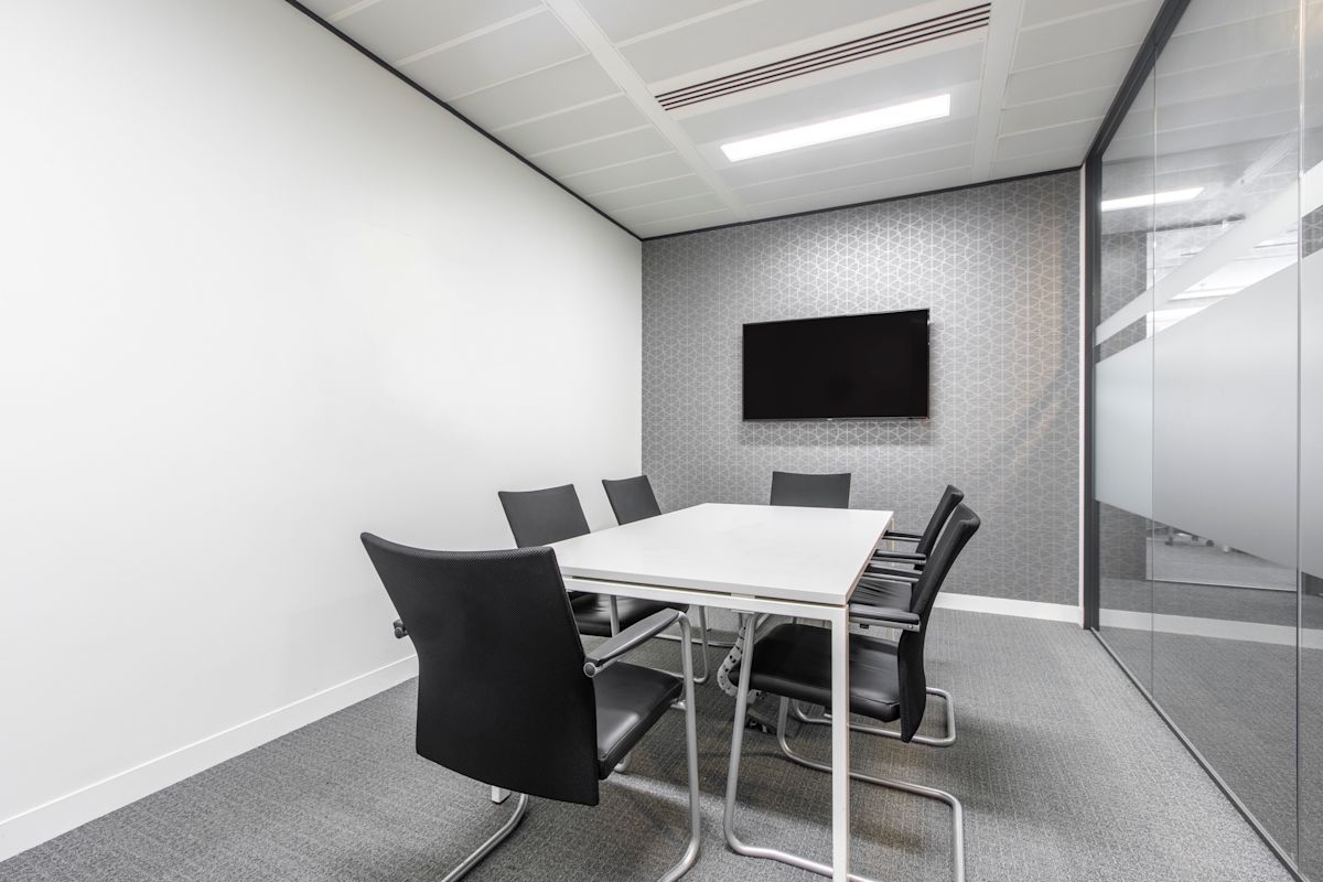 A modern conference room with a table, chairs, and a wall-mounted TV at 63 St Mary Axe, London.