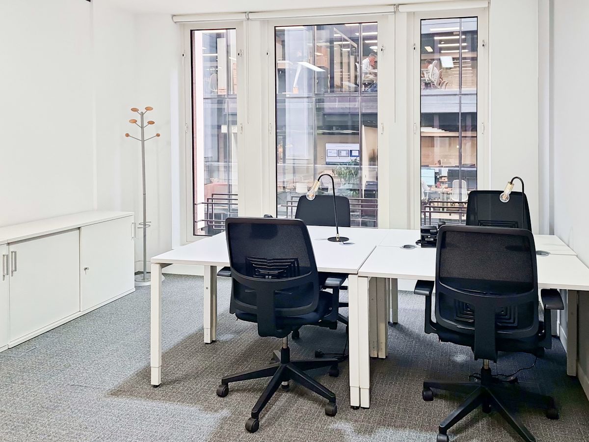 Modern office space in St Mary Axe 63, London, featuring desks, chairs, and large windows.