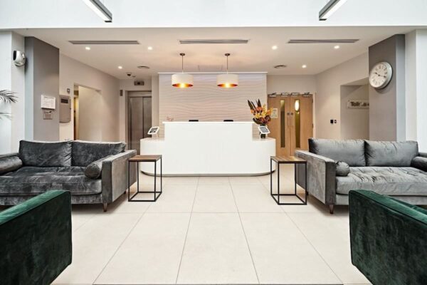 Modern reception area with grey sofas and a white desk at Victoria Avenue, London.