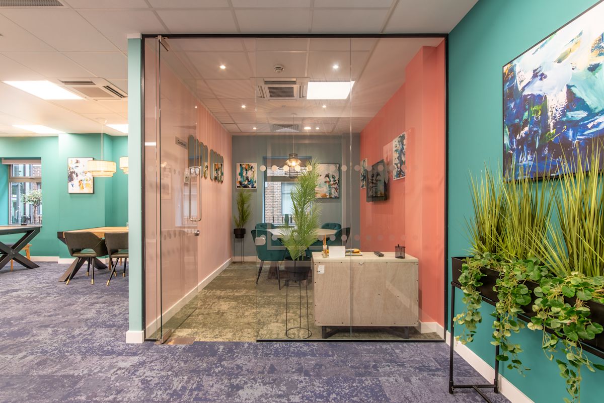 A modern office space with colorful walls, glass partitions, and contemporary decor.