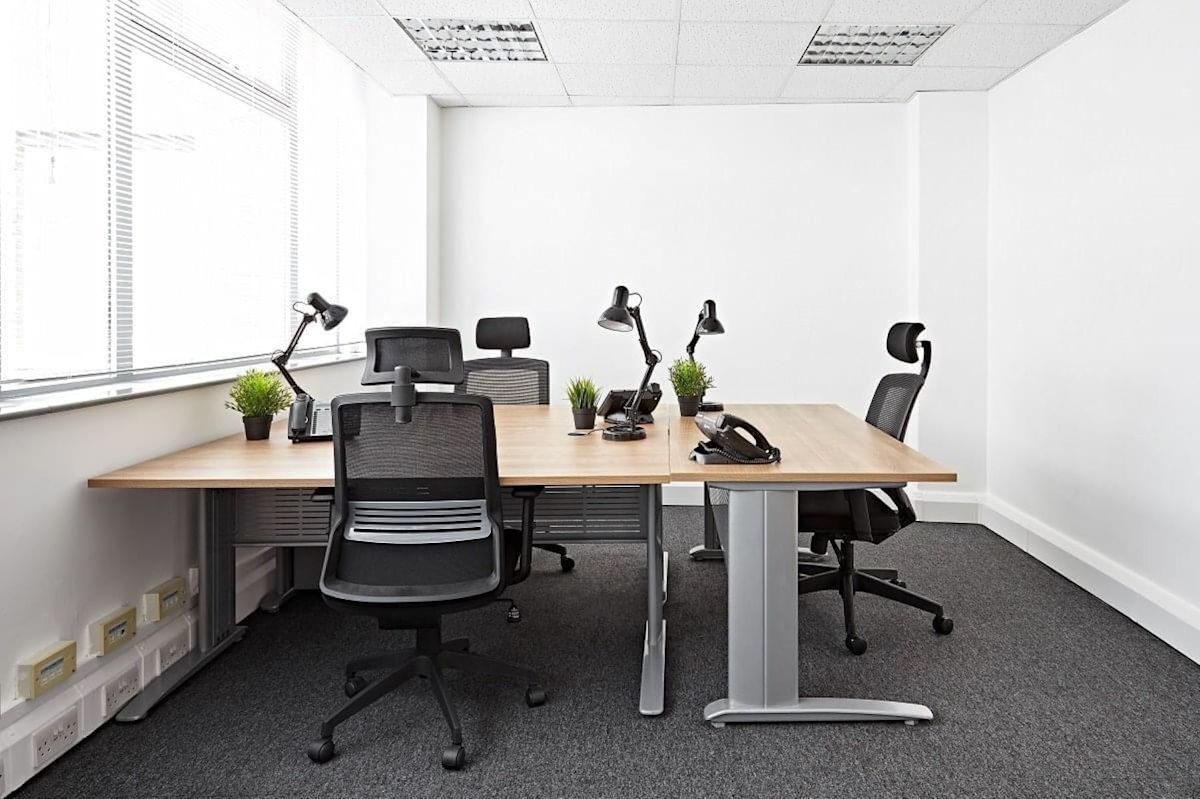 Modern, minimalist office space with desks, chairs, lamps, and small potted plants.