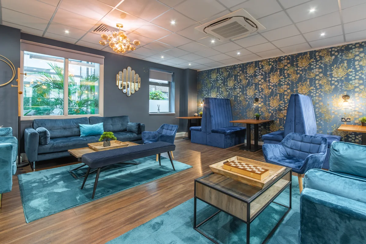 A stylish lounge area with blue furniture and floral wallpaper on Victoria Avenue, London.