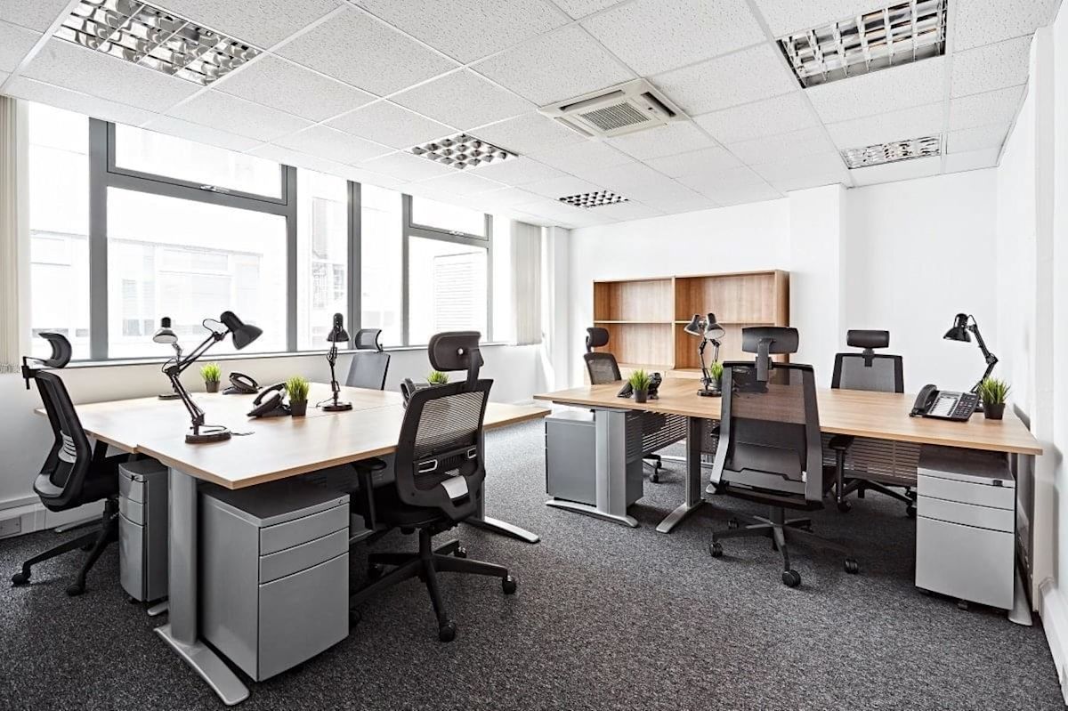 A modern office space in Victoria Avenue, London, featuring desks, ergonomic chairs, and large windows.