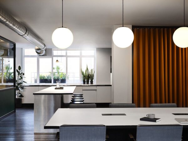 Modern office space with large windows, orange curtain, and minimalist furnishings at Wardour Street 151 in London.