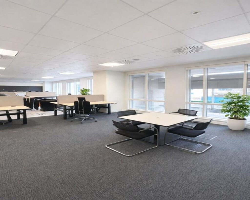 A modern office space at Westferry Circus 11 London, featuring desks, chairs, and large windows.