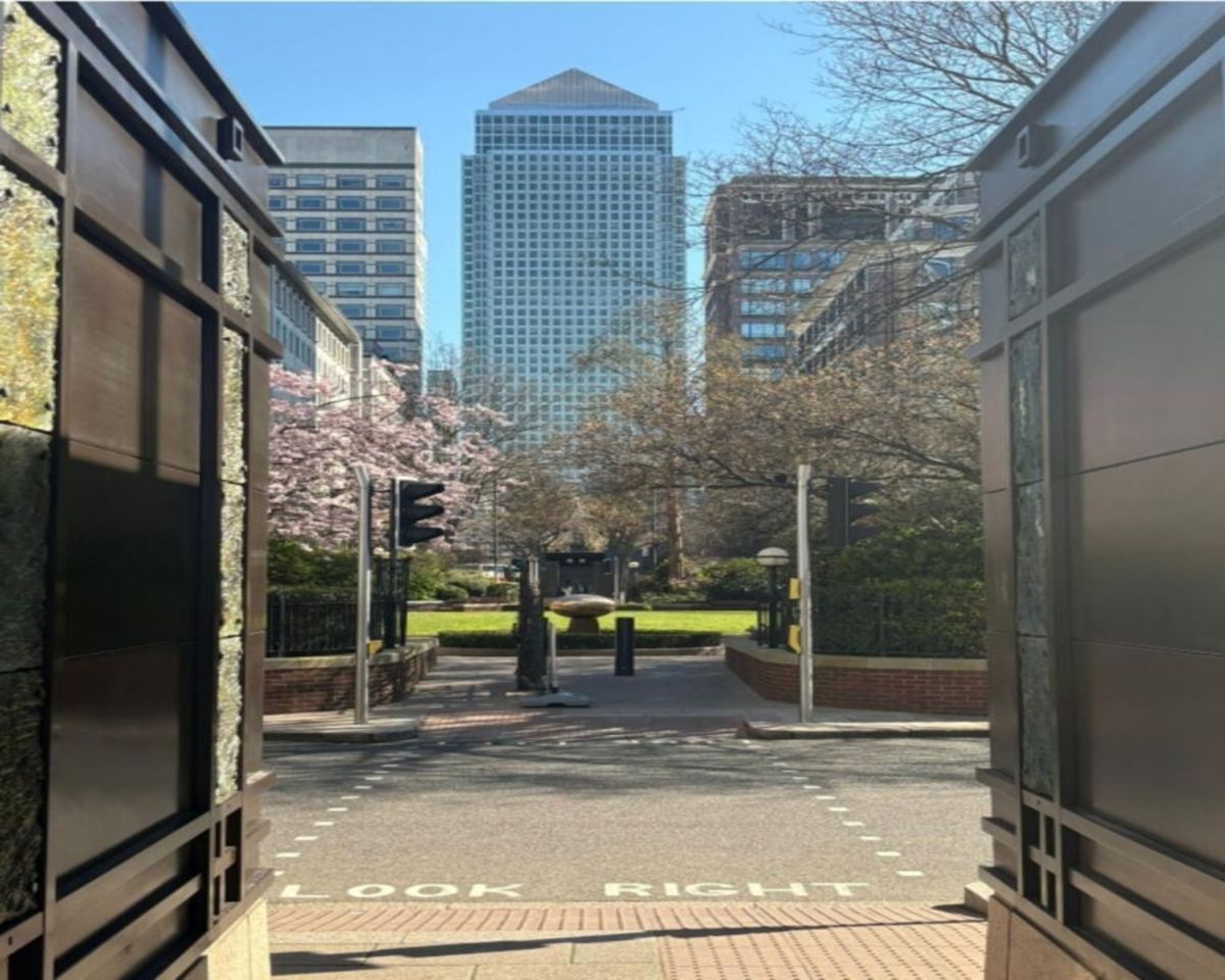 View of Westferry Circus in London with a prominent skyscraper in the background framed by modern buildings and greenery.