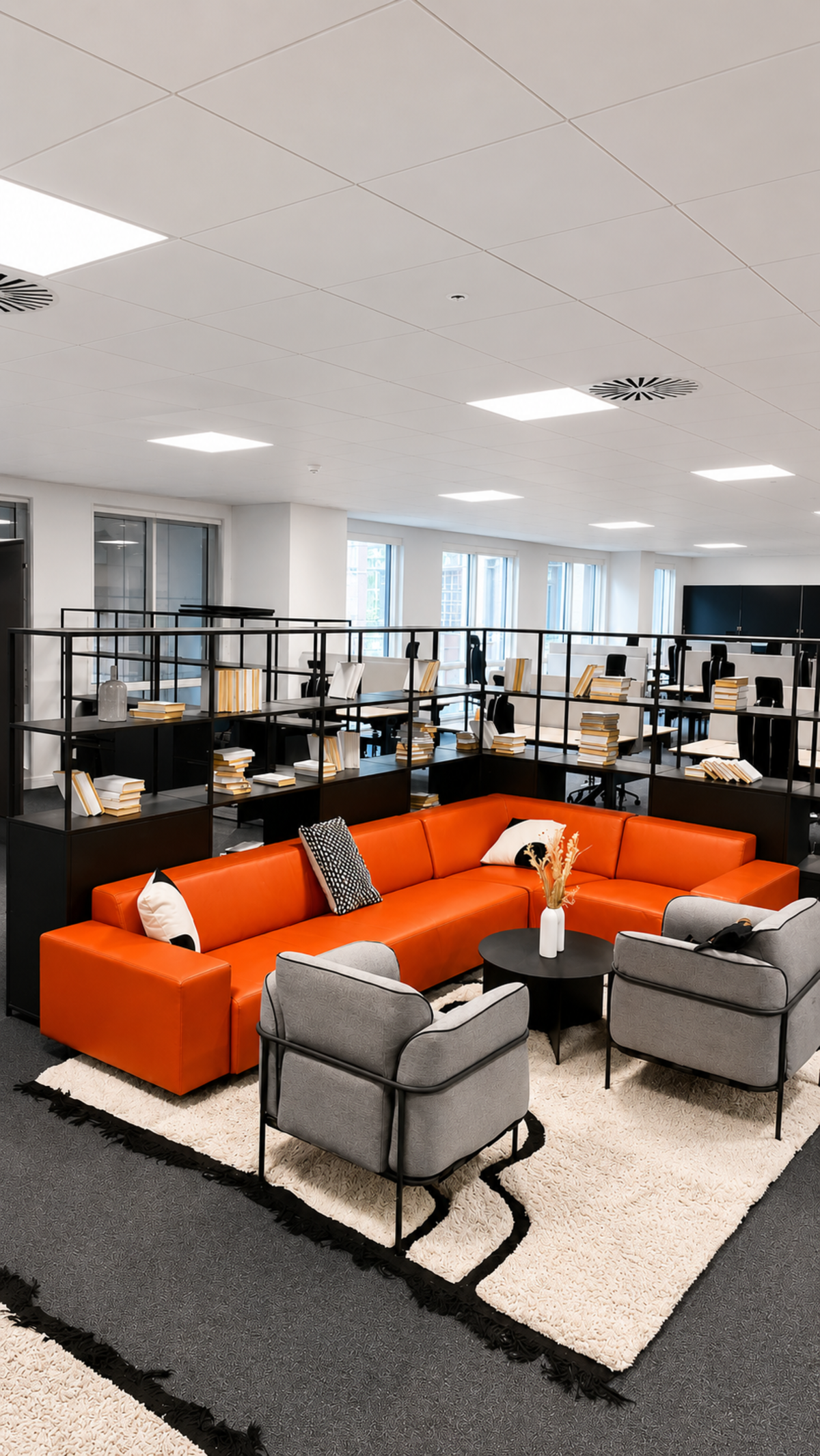 Modern office space with a vibrant red sofa and gray armchairs around a black coffee table at Westferry Circus 11, London.