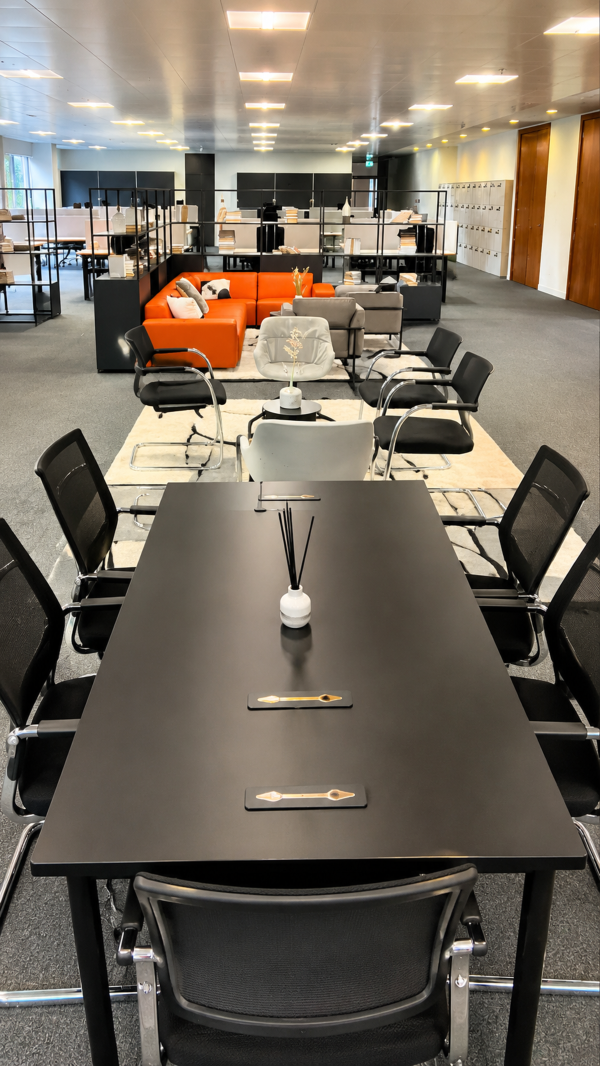 Modern open-plan office space at Westferry Circus 11 in London, featuring a conference table and a seating area with orange and gray furniture.